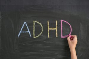 Child writing Abbreviation ADHD on a blackboard